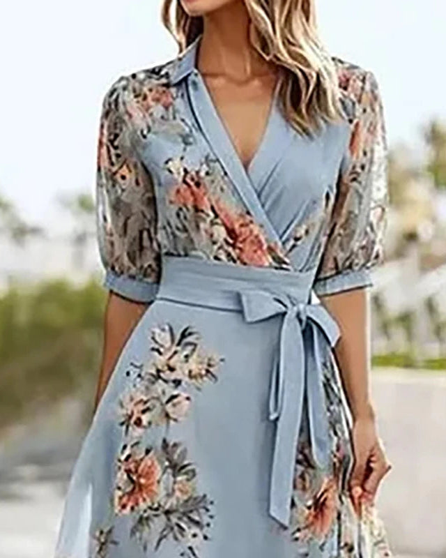 Woman wearing a light blue floral dress with a blurred outdoor background