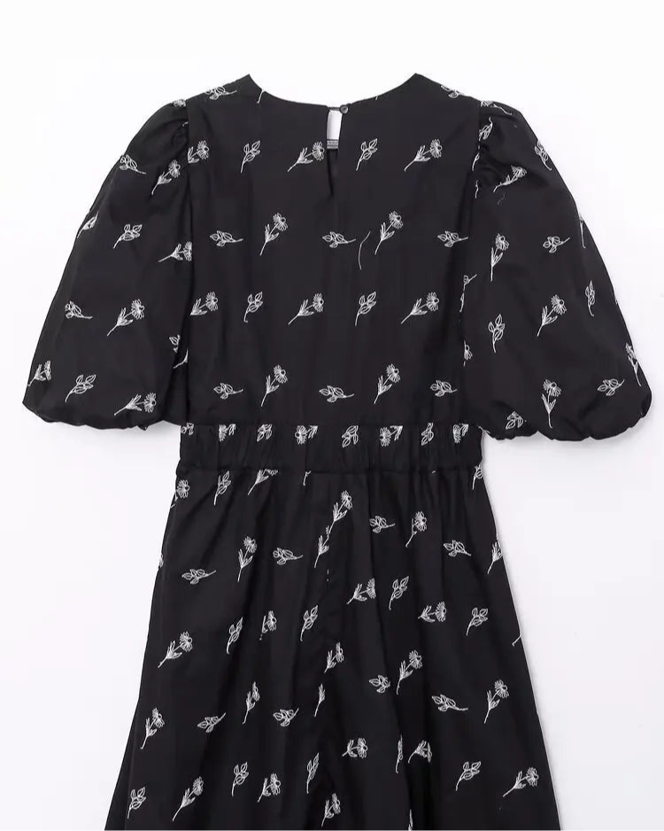 Black dress with white floral pattern on a white background