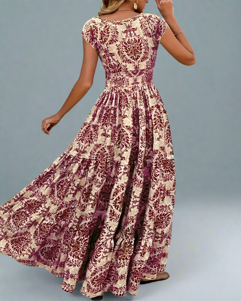 Woman wearing a long, patterned dress standing against a textured wall.