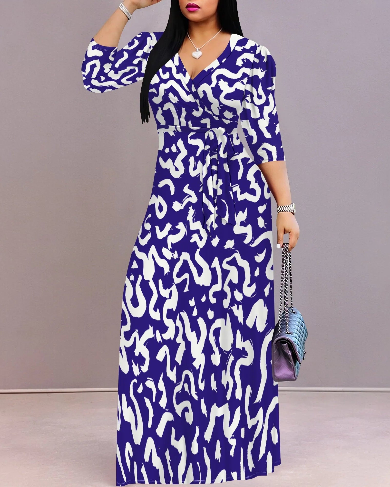 Woman wearing a blue and white patterned dress holding a matching handbag against a gray background