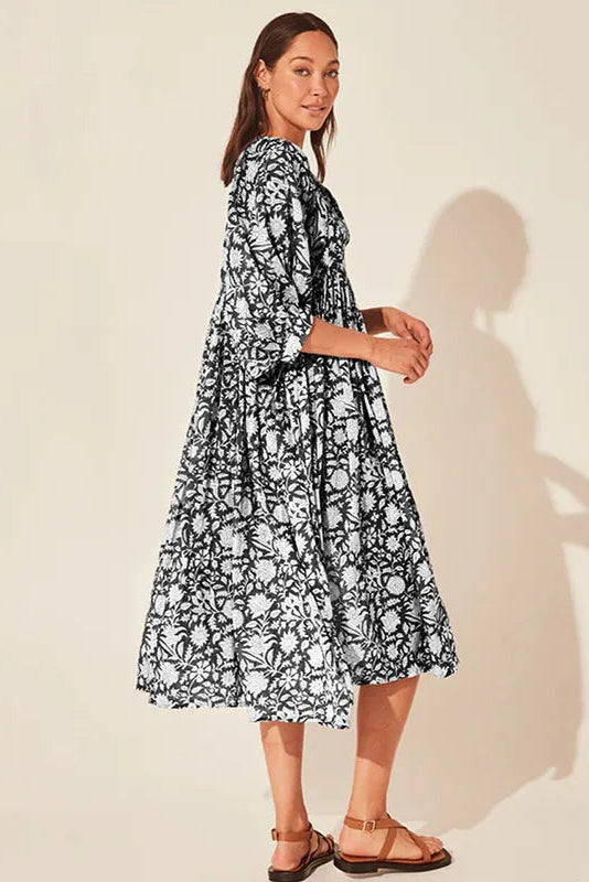 Woman wearing a black and white floral dress against a beige background