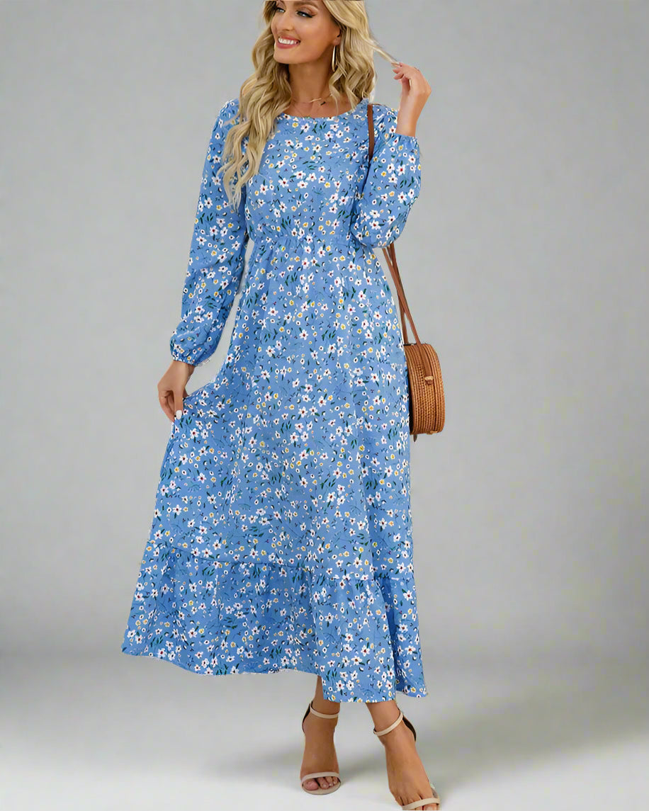 Woman wearing a blue floral dress with a white wall and plant in the background