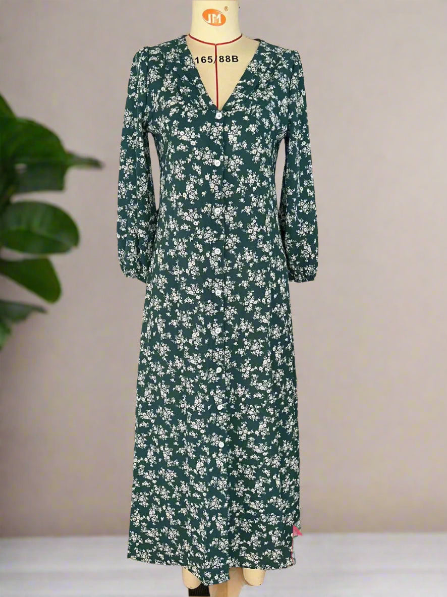 Green floral dress on a mannequin against a plain wall.
