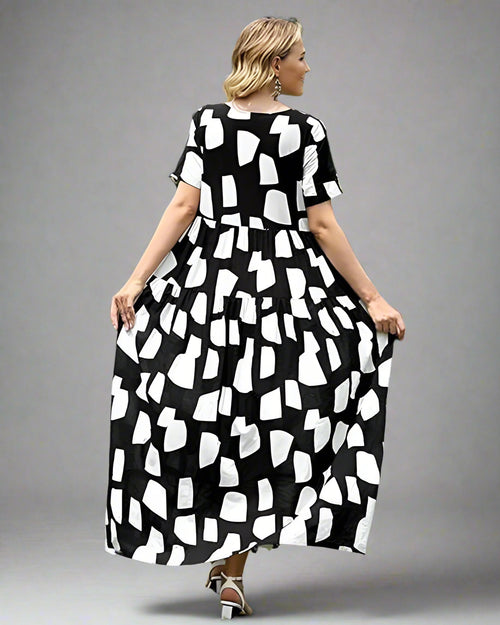 Woman wearing a black and white patterned dress standing on grass with a blurred background