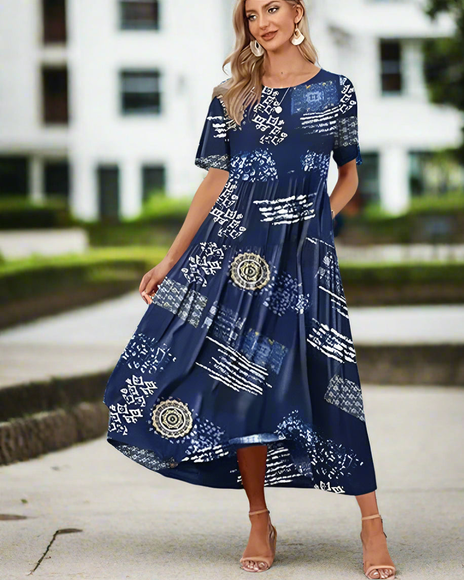 Woman wearing a blue patterned dress standing on a dock with palm trees and water in the background