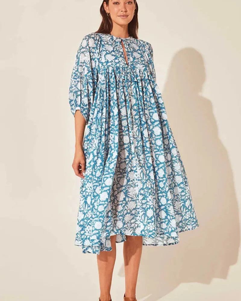 Woman wearing a blue floral dress against a plain background