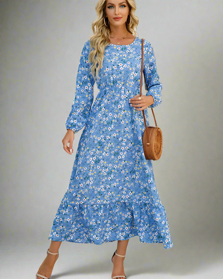 Woman wearing a blue floral dress holding a brown bag against a white wall.