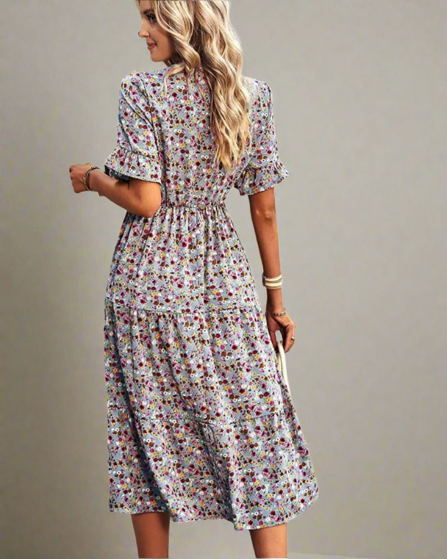 Woman wearing a floral dress standing on a street.