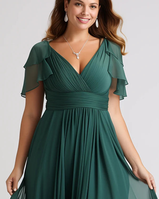 Woman wearing a green evening gown with ruffled sleeves on a plain background