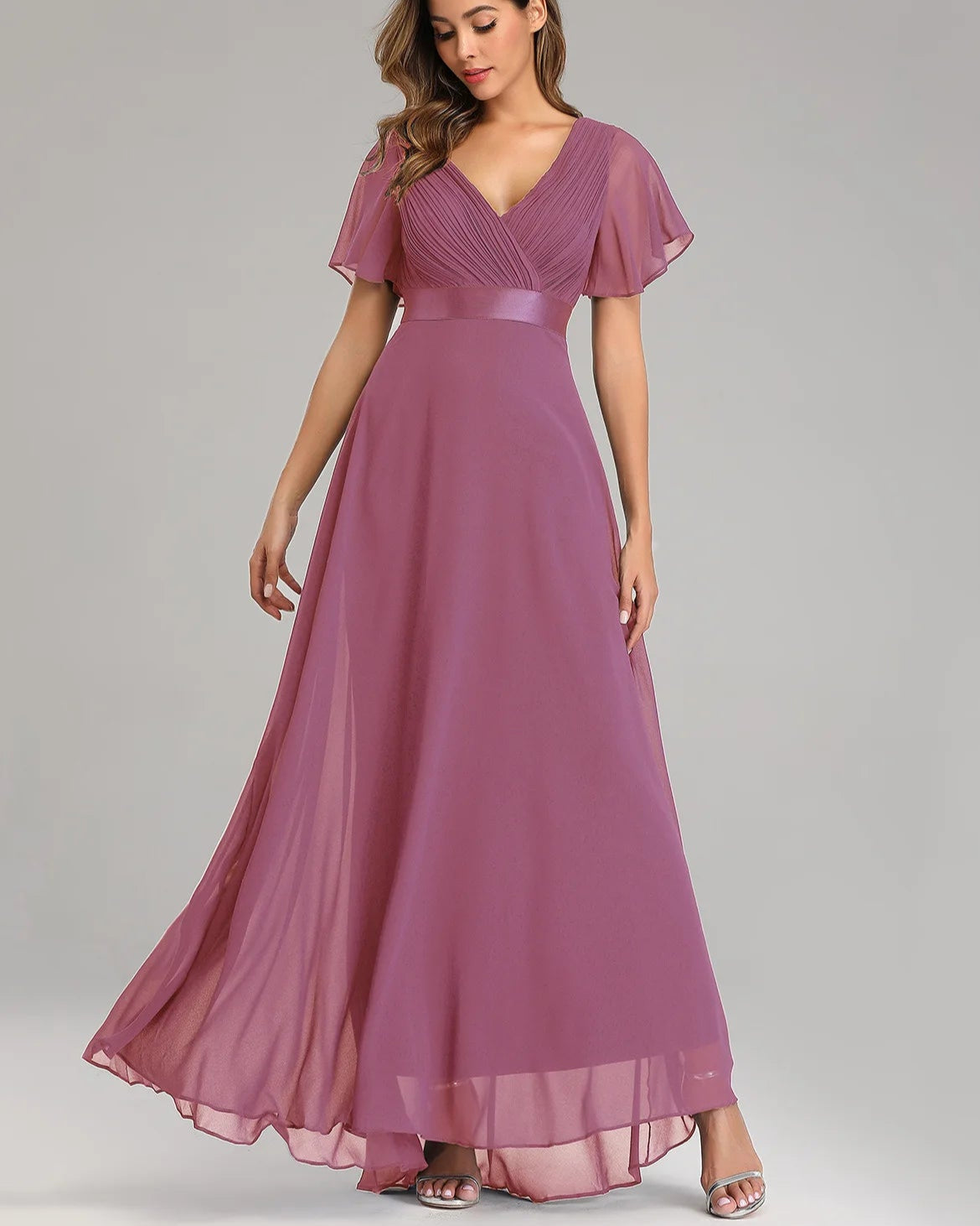 Woman wearing a long purple dress on a gray background